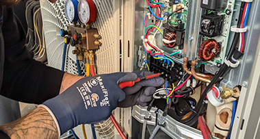 a person using a screwdriver for maintenance on an air conditioning unit