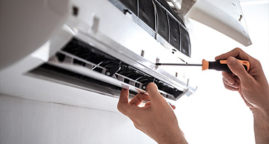 a person using a screwdriver to configure an air conditioning unit